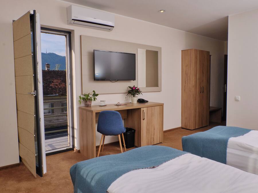 Een hotelkamer met een bed, een bureau met stoel, een televisie en een kledingkast.
