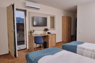 Une chambre d’hôtel comprenant un lit, un bureau avec une chaise, une télévision et une armoire.