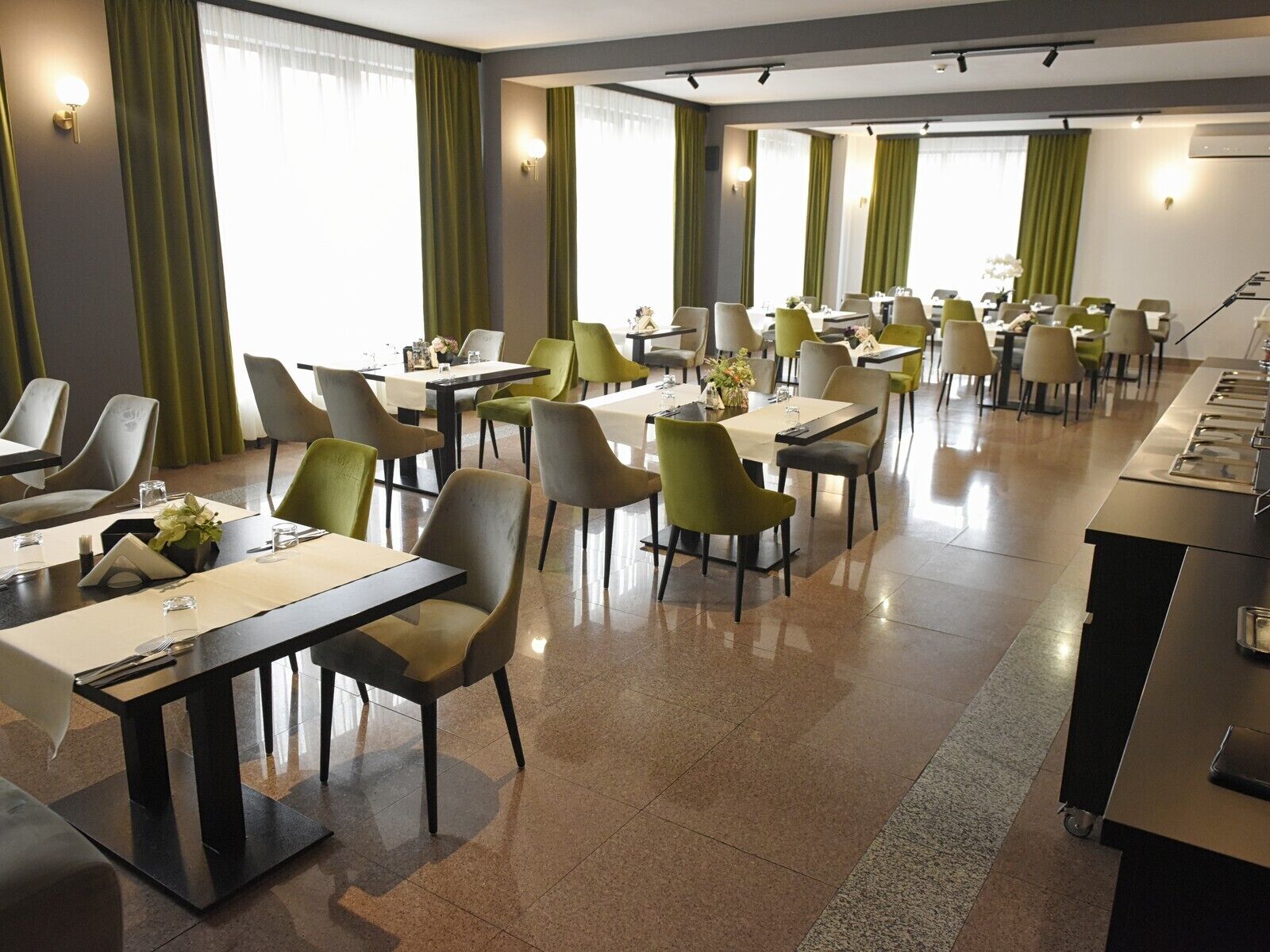Un comedor de hotel con varias mesas y sillas, dispuesto en un espacio amplio.
