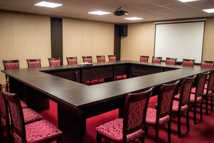 Une salle de conférence équipée d’une longue table et de chaises, d’un projecteur et d’un écran.