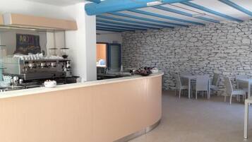 Une cuisine moderne avec un mur en pierre et un coin salon équipé de tables et de chaises.