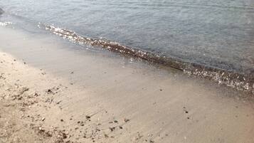 Ein sandiger Strand mit sanften Wellen, die an die Küste schlagen.
