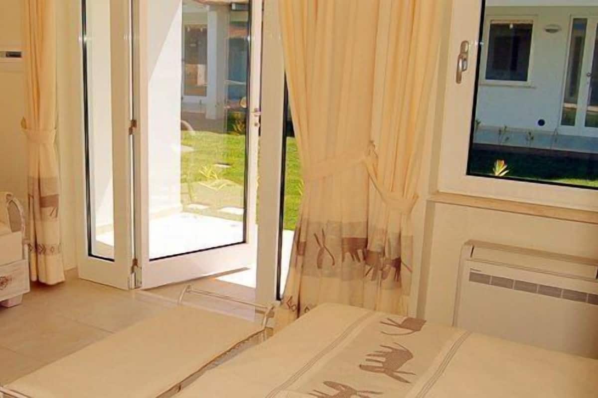 Ein Zimmer mit einer Couch, einem kleinen Tisch und einer Glasschiebetür zu einem Außenbereich.