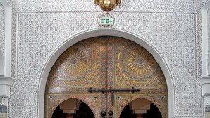 Een sierlijke entree met gedetailleerd tegeltapijt en een patroon vloer, die leidt naar een ruimte met gedekte tafels.