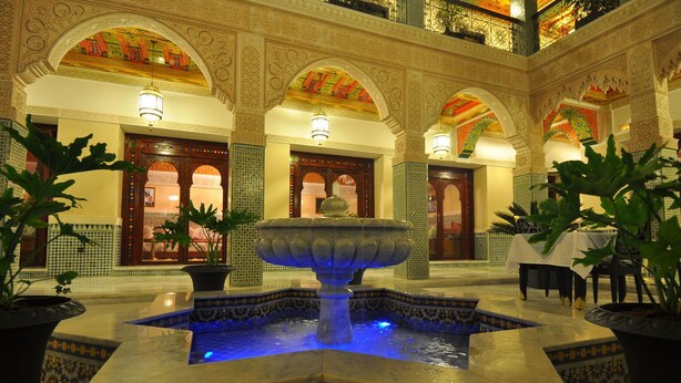 A courtyard with a central fountain, tiled walls, and arches.
