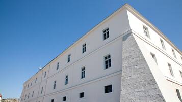 Ein mehrgeschossiges Gebäude mit weißer Fassade und einem Steinsockel.