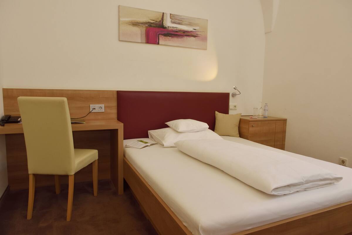 Una habitación de hotel con cama, escritorio y silla.