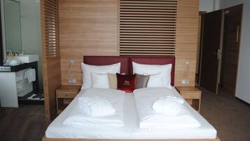 Ein Hotelzimmer mit einem großen Bett, einem Holzkopfstück, zwei Nachttischen, einem Spiegel und einem Kleiderschrank.