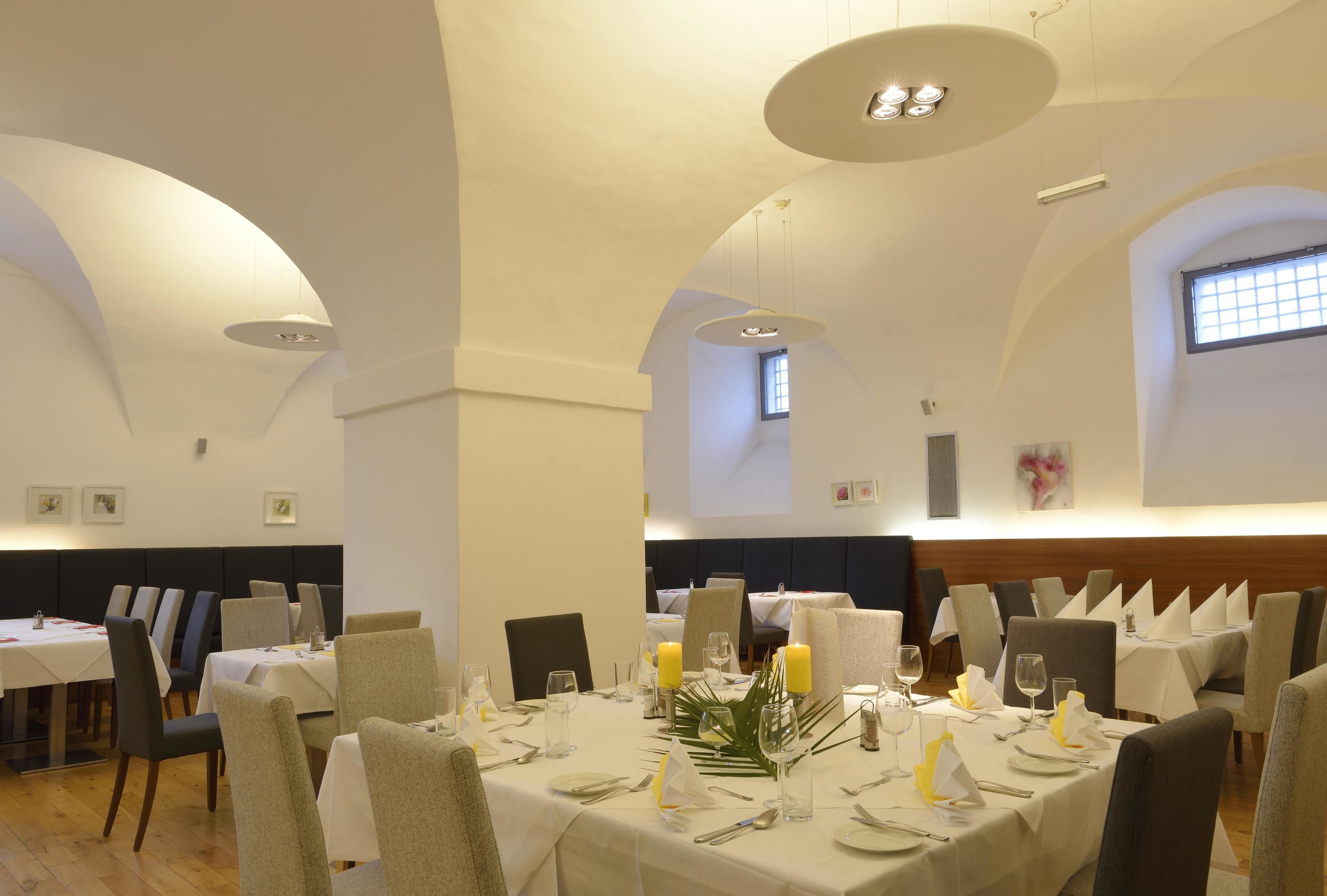 A dining area with tables set for a meal, featuring white tablecloths, chairs, and candles.