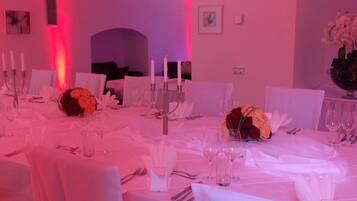 Un comedor formal con manteles blancos, candelabros y centros de mesa florales.