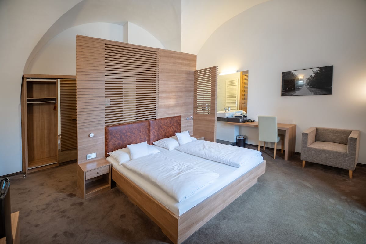 Un dormitorio moderno con una cama grande, un cabecero de madera, un escritorio y una silla.