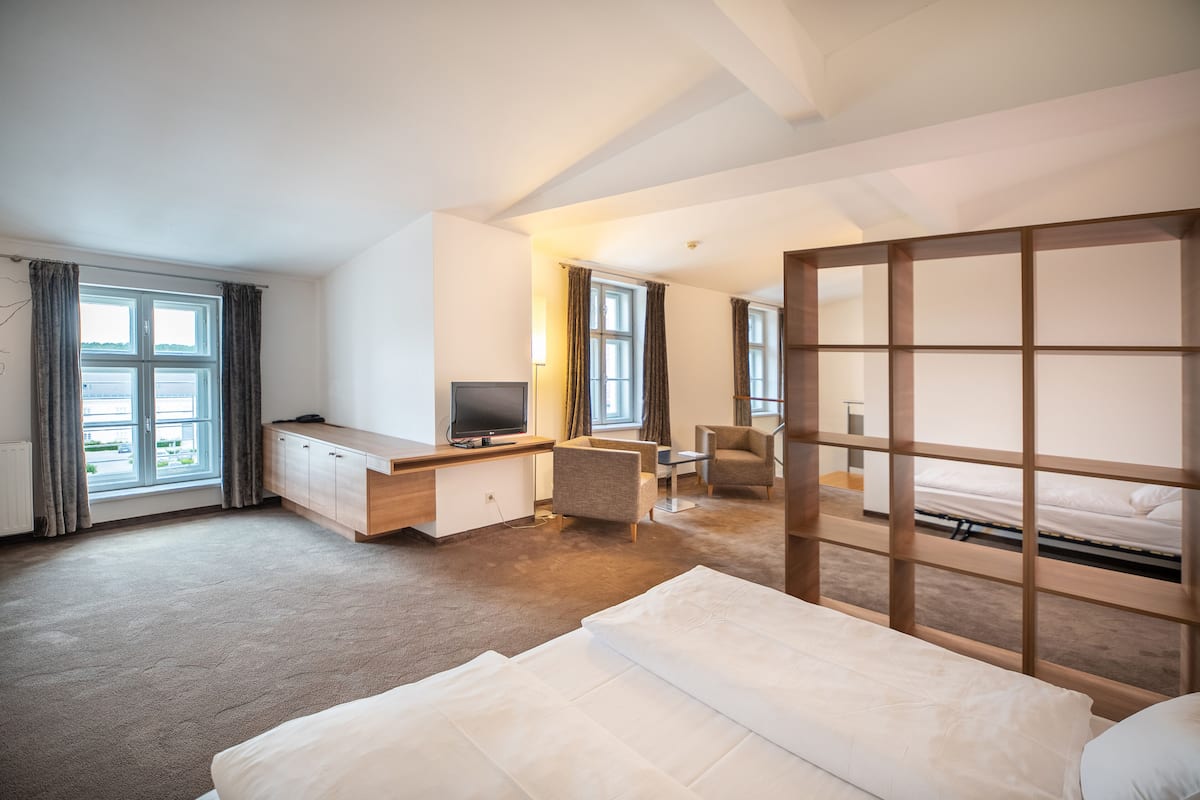 Una habitación de hotel moderna con una cama grande, un escritorio con televisión, una silla y vistas al exterior.