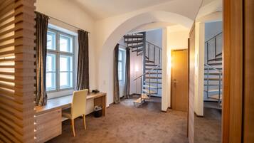 A room with a desk, chair, and a spiral staircase.