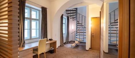 A room with a desk, chair, and a spiral staircase.