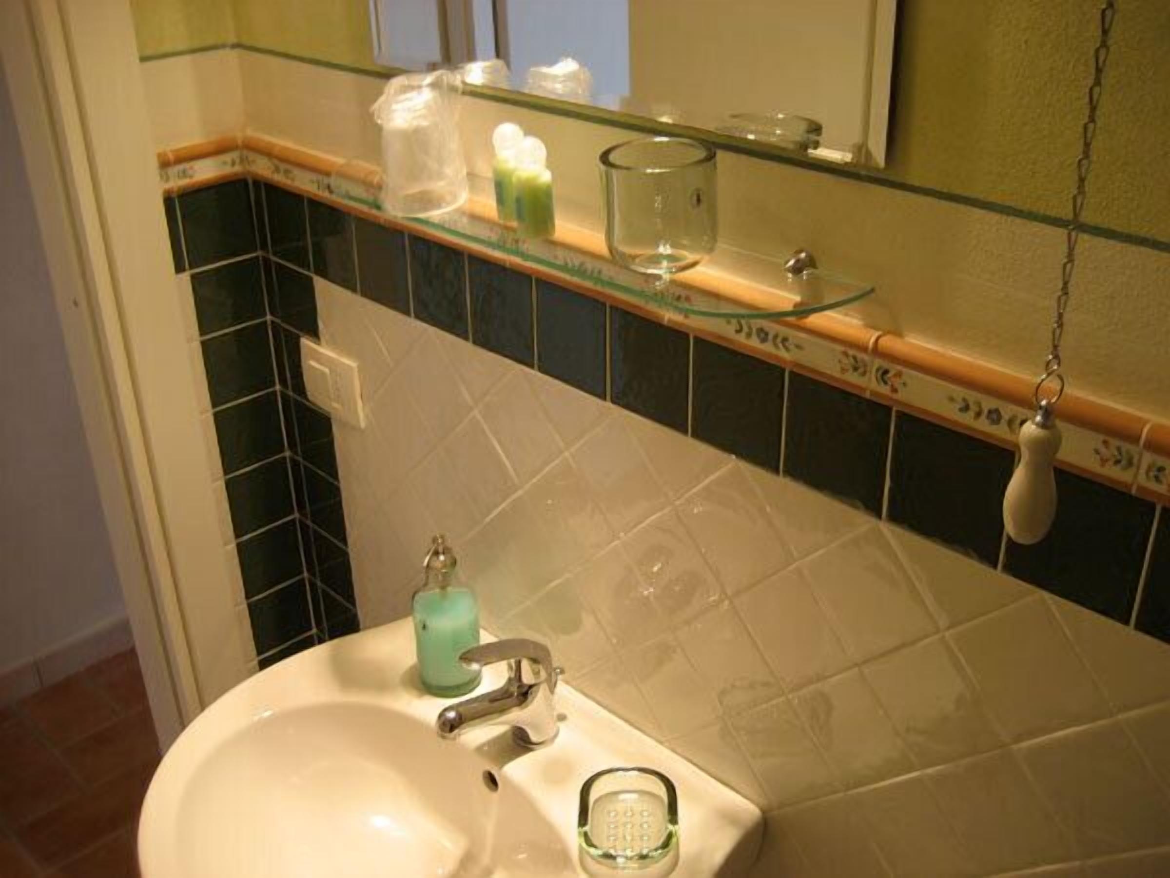 A bathroom with a sink, mirror, and toiletries on the countertop.