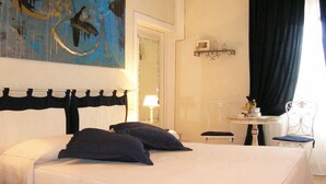 A hotel room with a bed, a chair, a small table, and a painting on the wall. - B&B Il Moscondoro (Montopoli in Val d'Arno)