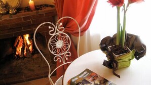 A cozy room with a fireplace, a metal chair, a table with a magazine, and a potted plant. - B&B Il Moscondoro (Montopoli in Val d'Arno)