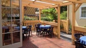 A covered patio area with brick flooring and wooden furniture. - Haus Stoertebeker Appartements - Hotel Garni (Lubmin)