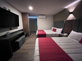 Een hotelkamer met twee bedden, een televisie, een bureau en een spiegel.