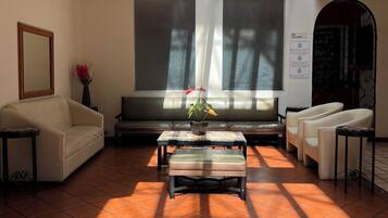 Un salón amplio con techo alto, ventanas grandes y piso de baldosas.