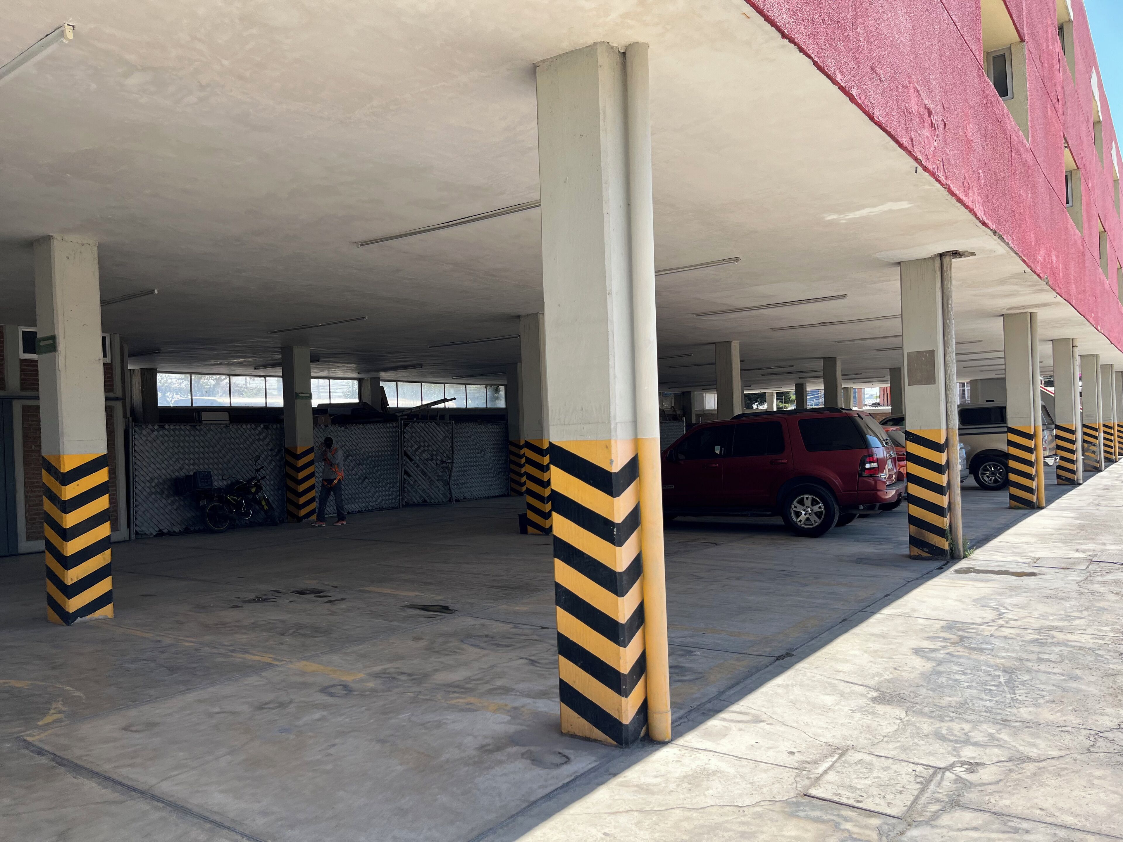 A multi-level parking garage with concrete pillars and striped safety markings.