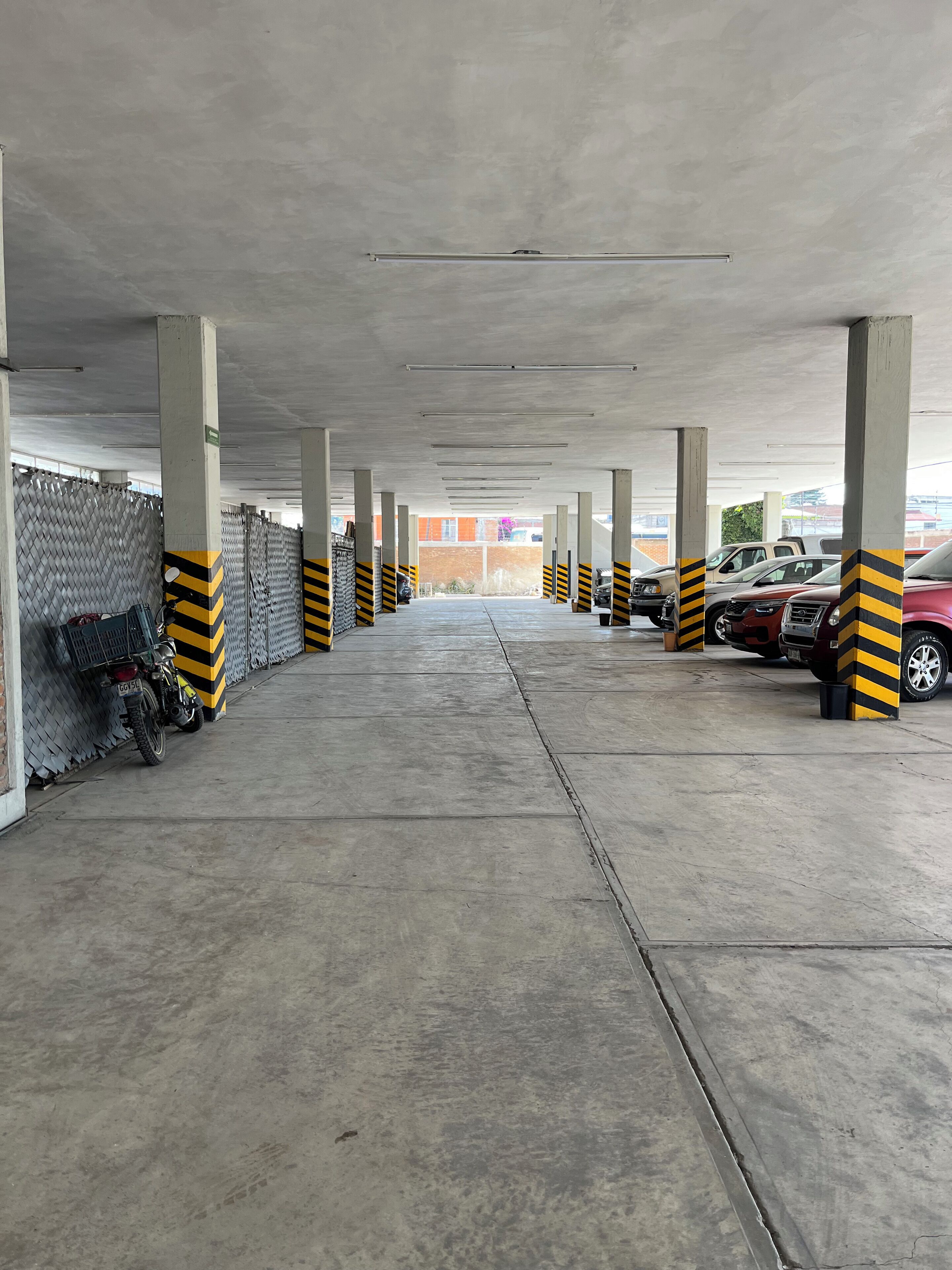 Un aparcamiento subterráneo con pilares de hormigón y un pasillo central.