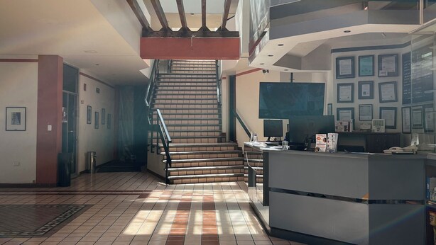 A spacious lobby with a staircase, a reception desk, and framed certificates on the wall. - Hotel Granada (Puebla)