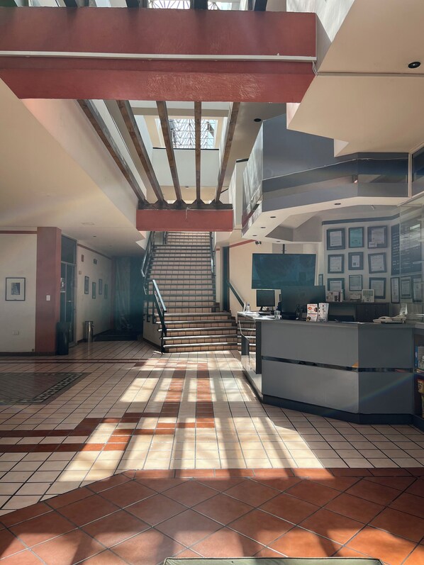 A spacious lobby with a staircase, a reception desk, and framed certificates on the wall.