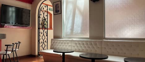 Un rincón acogedor con un sofá y dos mesas redondas, una televisión y un arco decorativo.