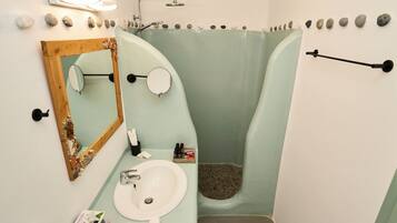 A bathroom with a sink, mirror, and shower.
