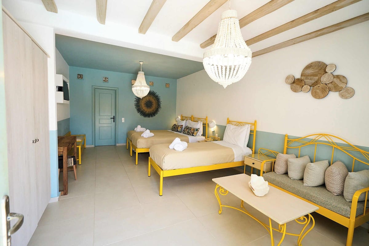 Quarto com duas camas, um sofá, uma mesa e um candelabro.