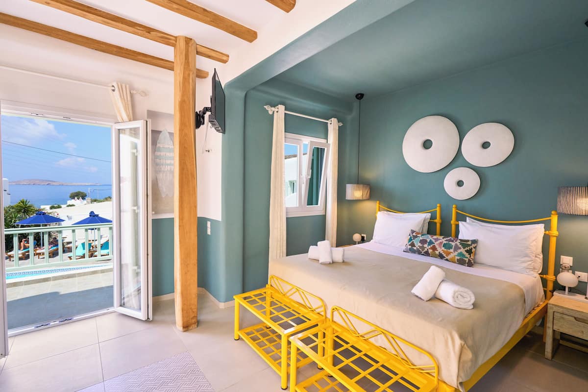 Um quarto com uma cama, uma janela e vista para o mar.