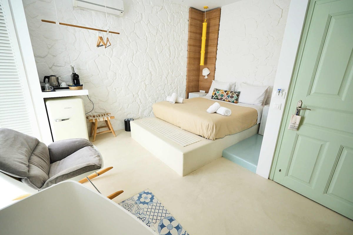 Quarto com cama, mesa de cabeceira e escrivaninha com cadeira.