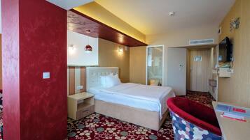 A hotel room with a bed, bedside table, and a red chair.