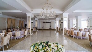 A spacious hall with a marble floor, elegant chandeliers, and rows of tables with chairs, suggesting a formal event setting. - Hotel Craiovita (Craiova)