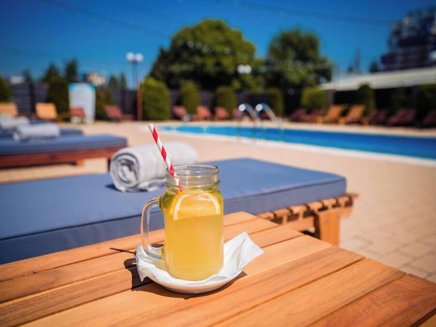 Una mesa de madera con una jarra de limonada, un popote rayado y una servilleta.