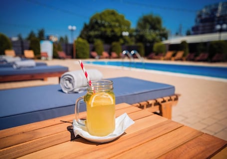 Una mesa de madera con una jarra de limonada, un popote rayado y una servilleta.