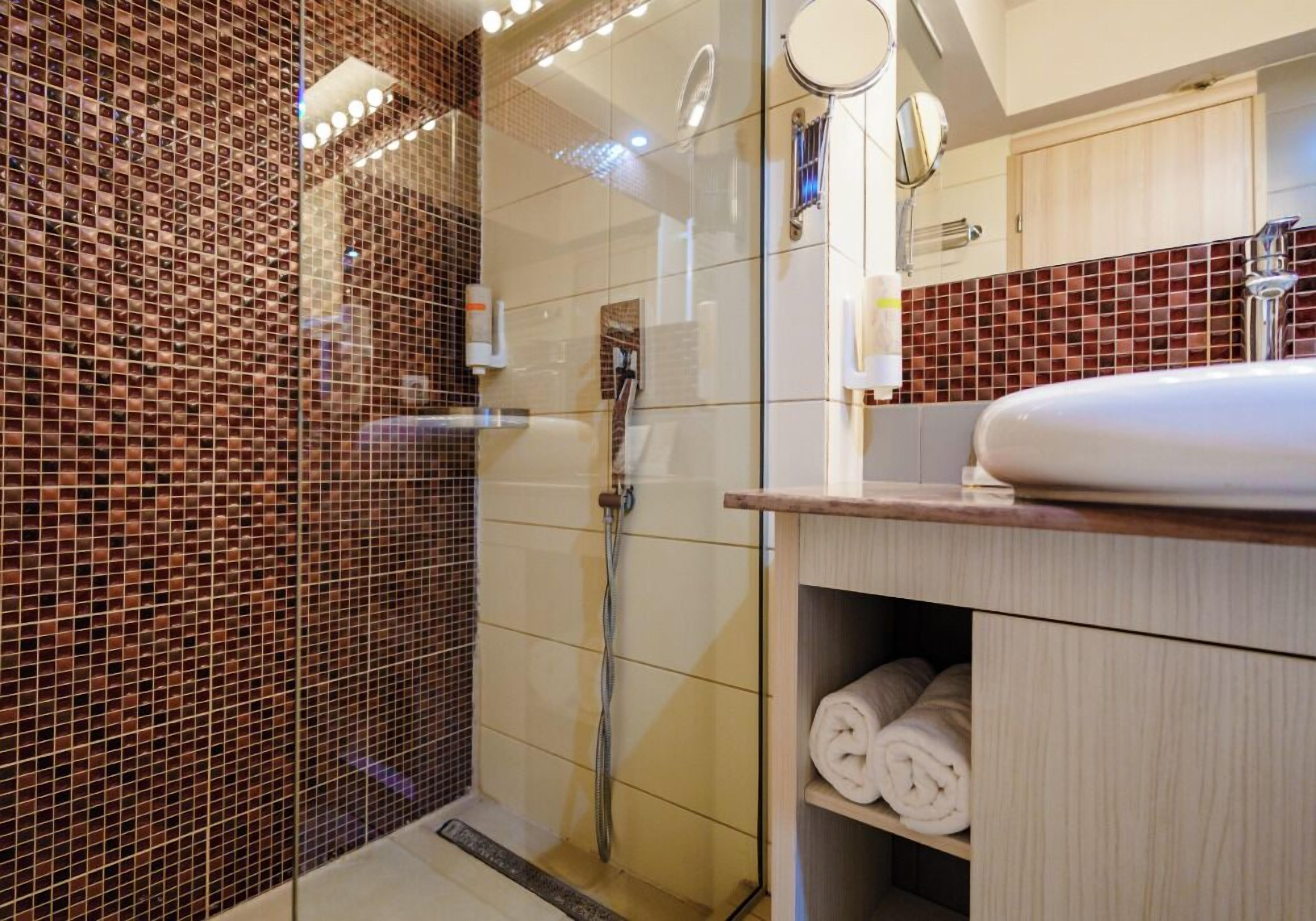 A modern bathroom with a glass-enclosed shower, a white sink, and a mirror.
