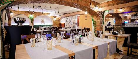 Un restaurante con arcos de ladrillo, mesas dispuestas con vasos y cubiertos, y una zona de bar.