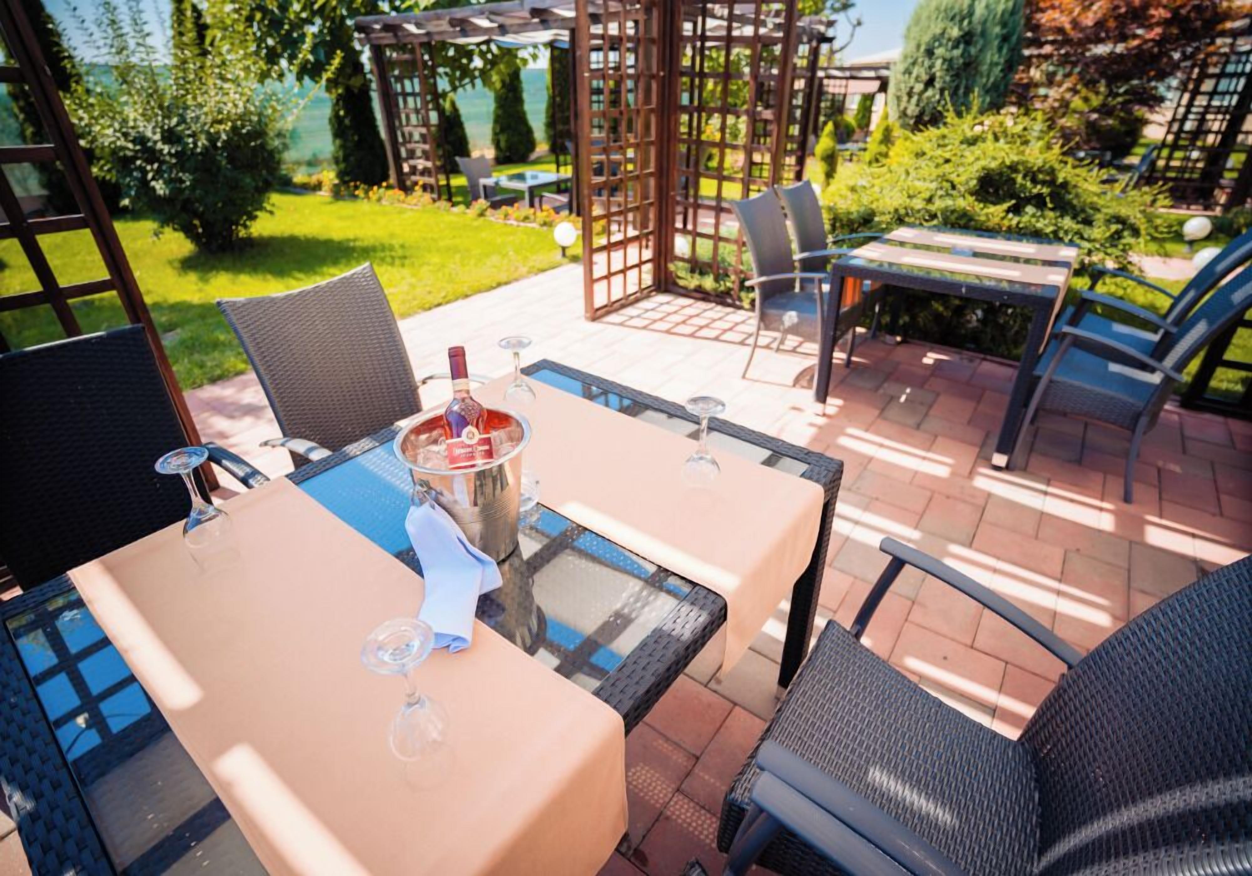Une terrasse extérieure avec des tables et des chaises, une pergola et une vue sur la mer.