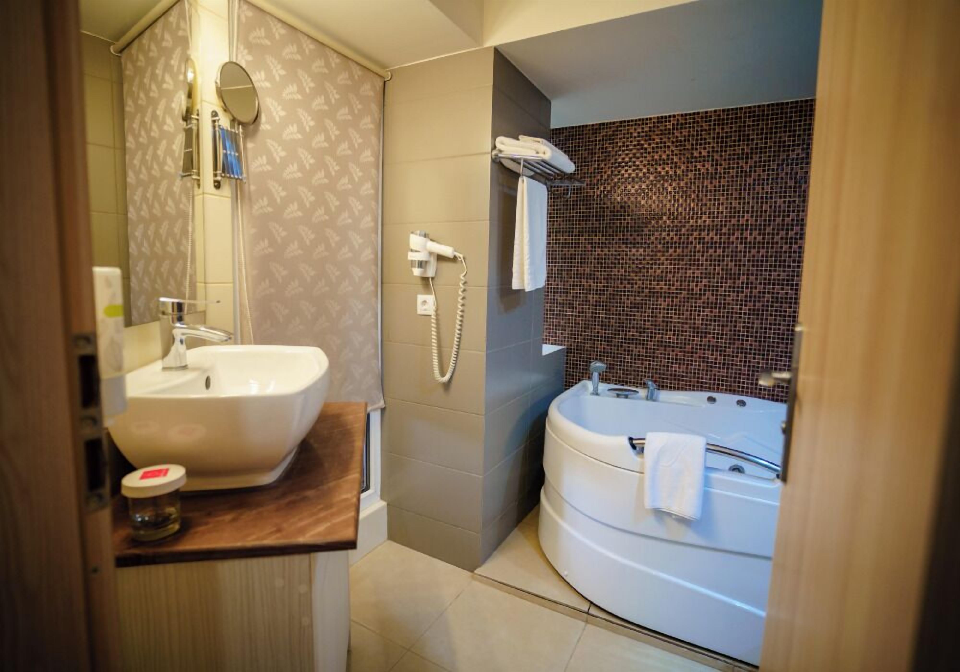 Un baño con lavamanos, espejo, toallero y bañera.
