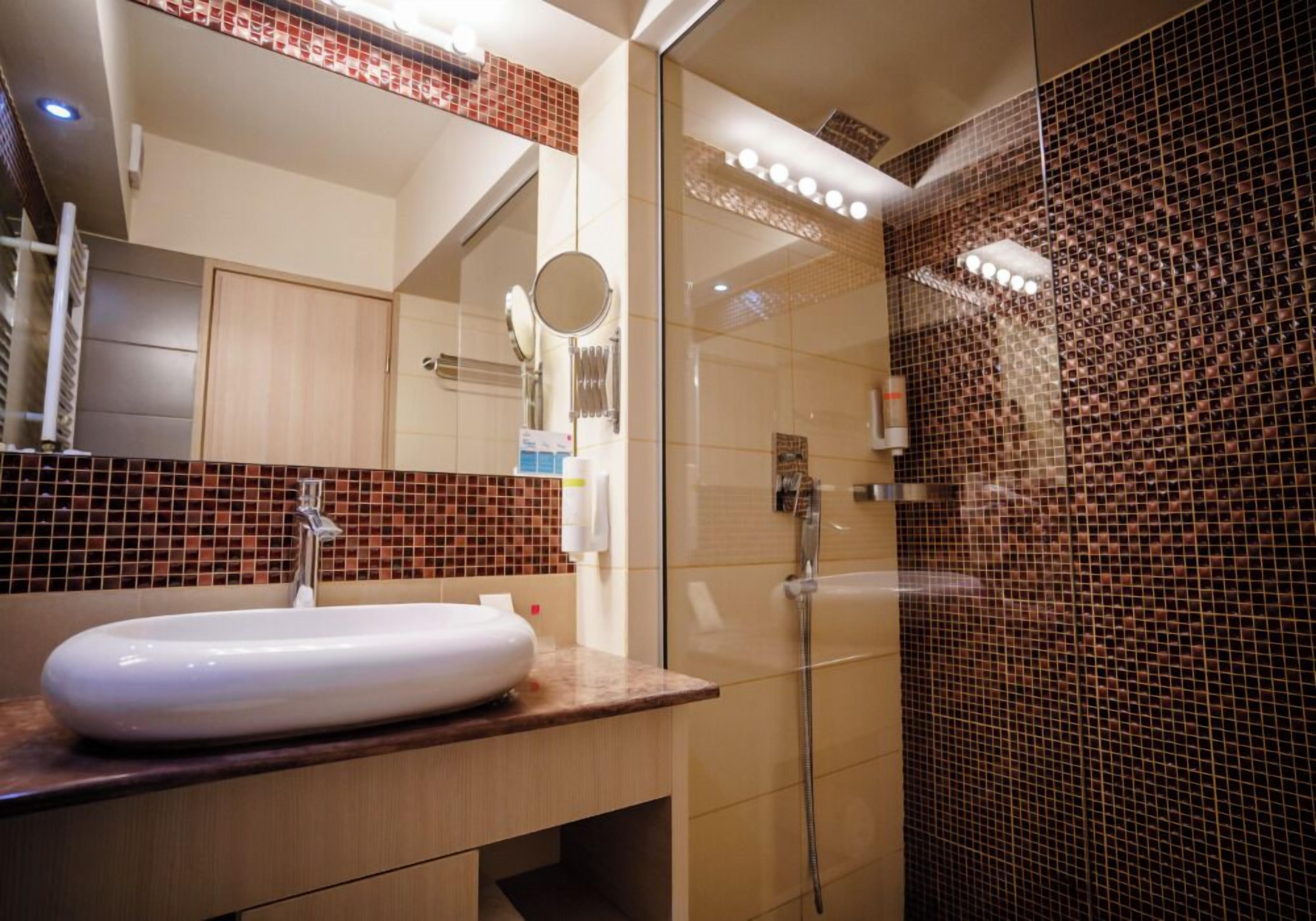 Un bagno moderno con uno specchio grande, un lavandino e una doccia.