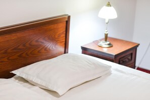 Una cama con cabecera de madera y almohada blanca.