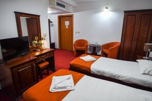 Habitación de hotel con dos camas, un escritorio con televisor y dos sillas.