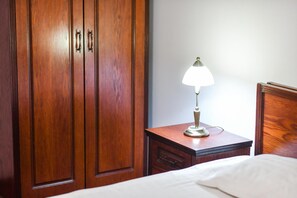 Un armario de madera con dos puertas y una mesita de noche con una lámpara.