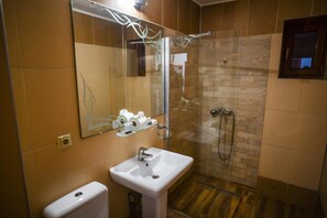 A bathroom with a white sink, a mirror, a glass-enclosed shower, and a toilet. - Hotel Elyon Dej (Dej)
