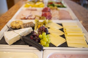 A cheese and fruit platter with various cheeses, grapes, and crackers.