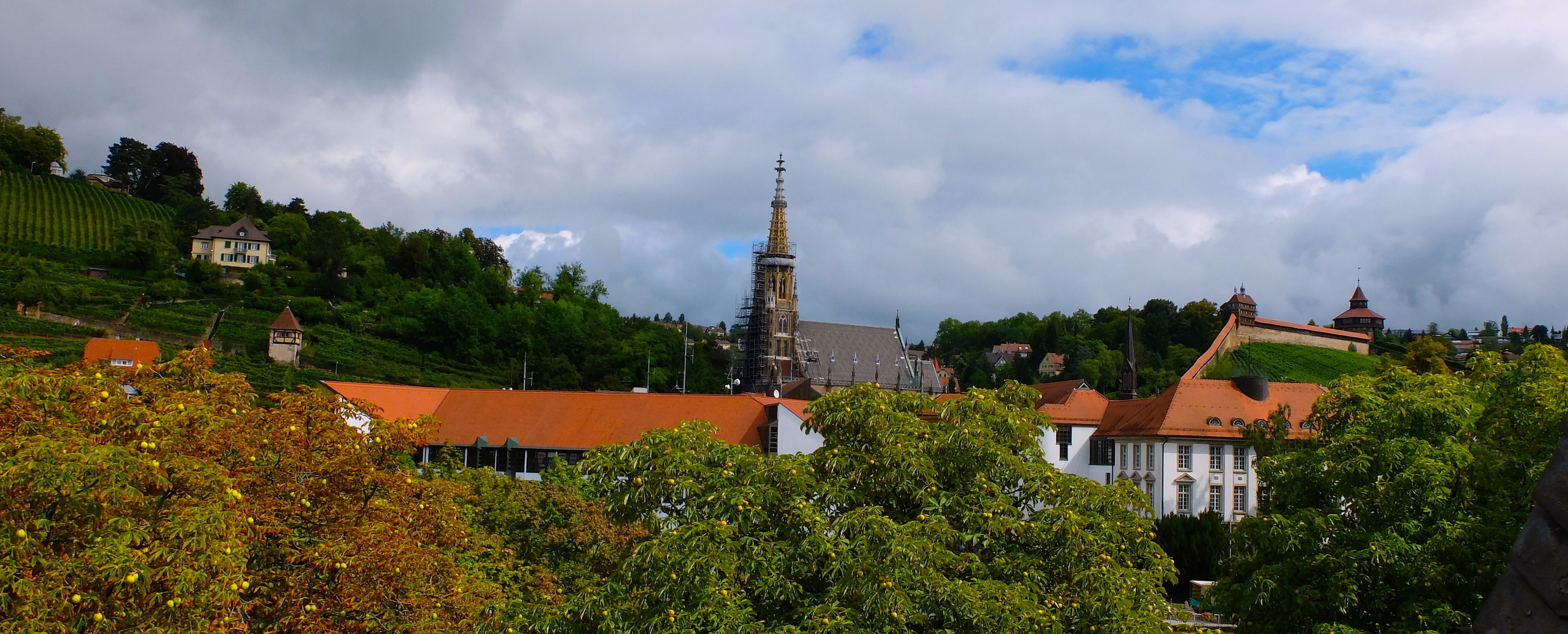 A historic building with a prominent tower and a red-roofed structure in the foreground.