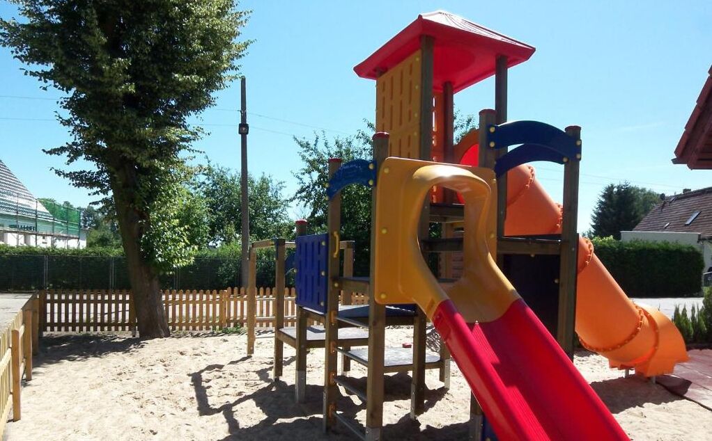 Ein Spielplatz mit Rutsche, Klettergerüsten und einem Sandbereich.