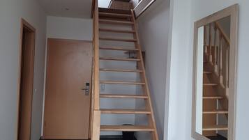 A wooden interior staircase with a skylight above, leading to an upper floor.